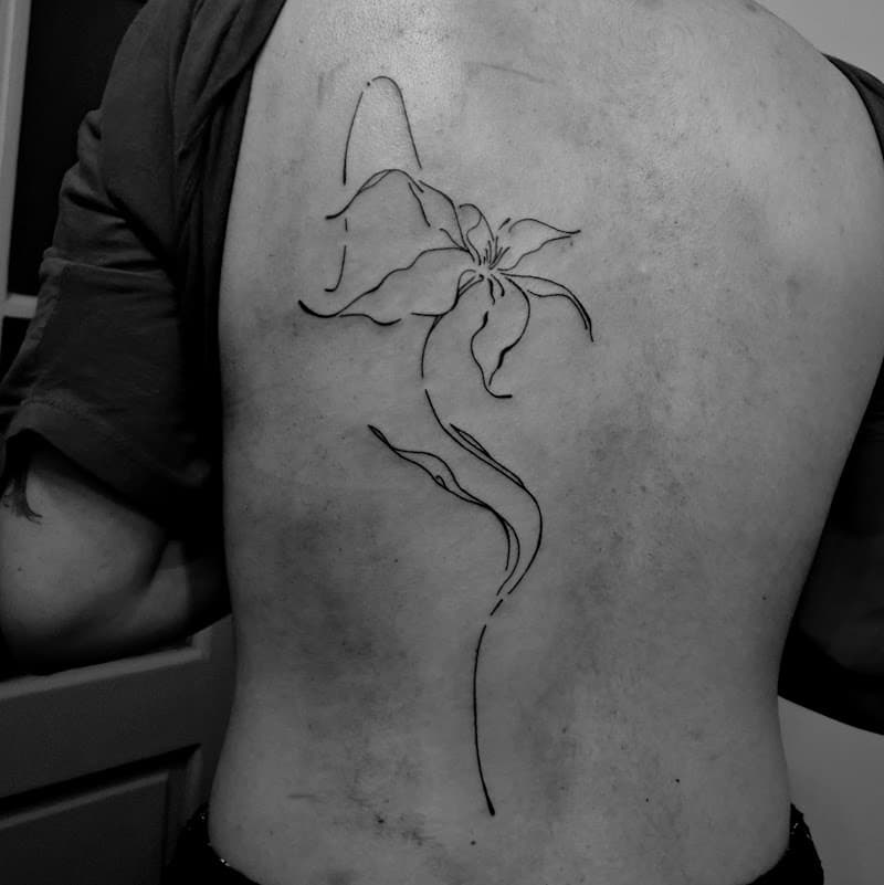 Minimalistische fineline lelie tattoo op de rug.
