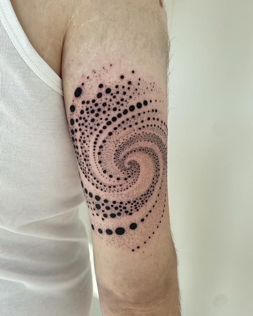Dotwork spiraal van stippen op de bovenarm.
