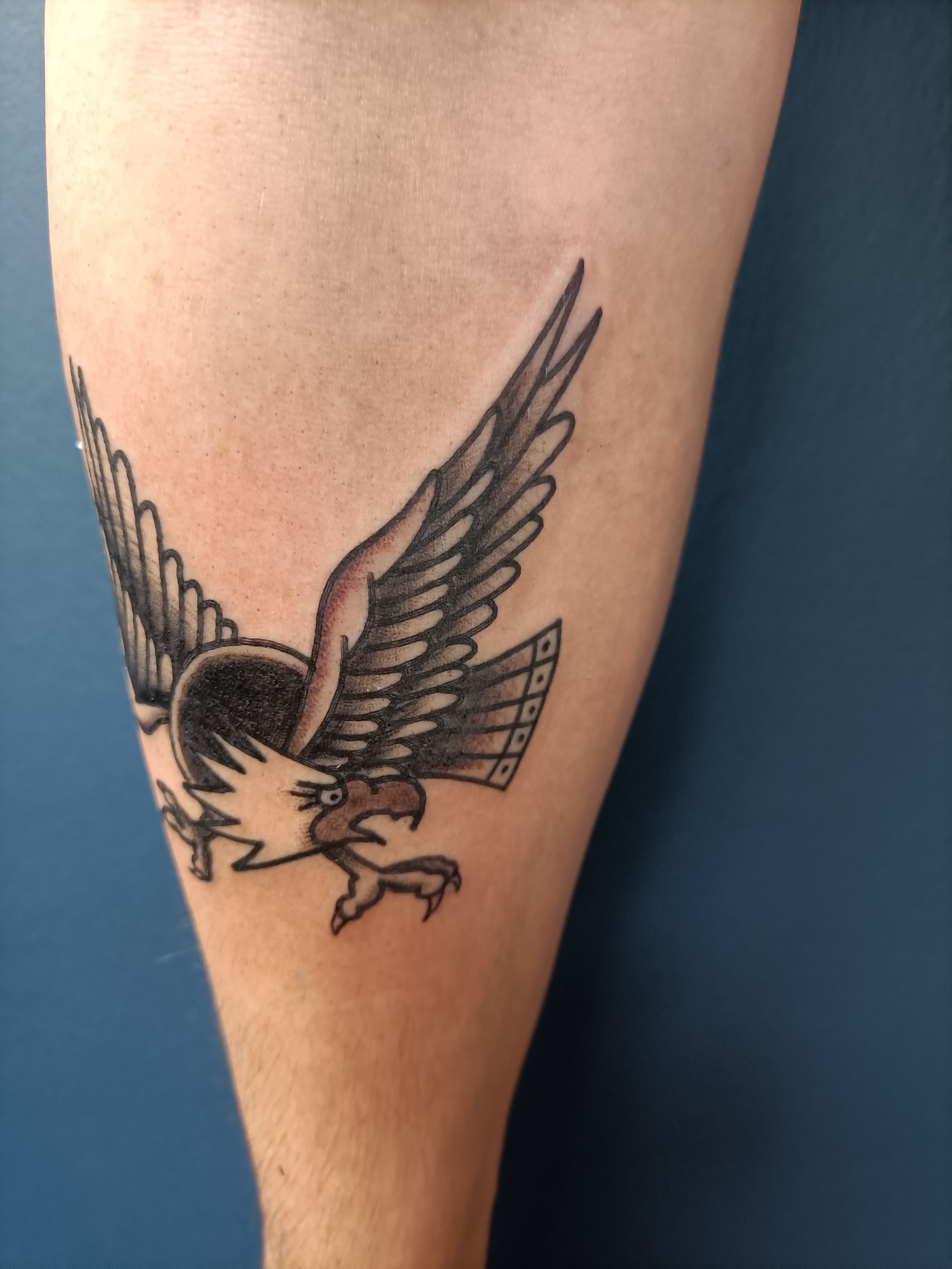 Traditionele adelaar tattoo in vlucht op het onderbeen.
