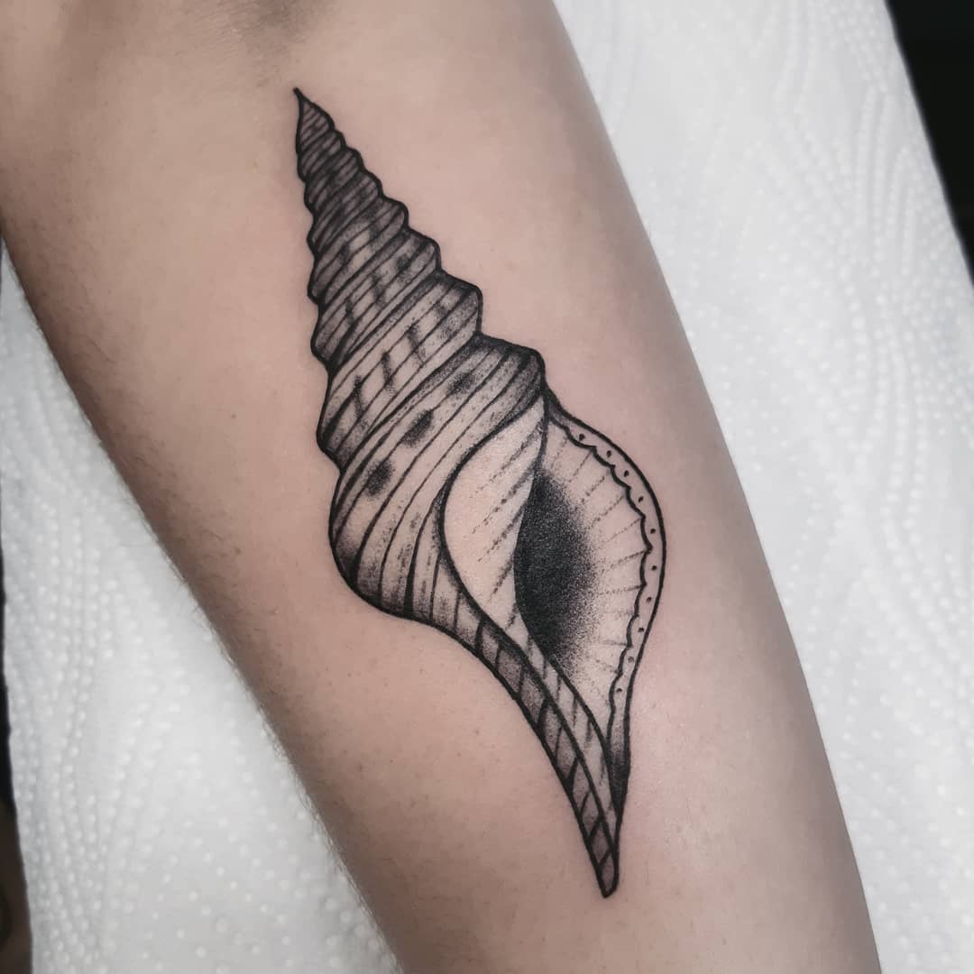 Gedetailleerde zwart-wit schelp tattoo op de onderarm.