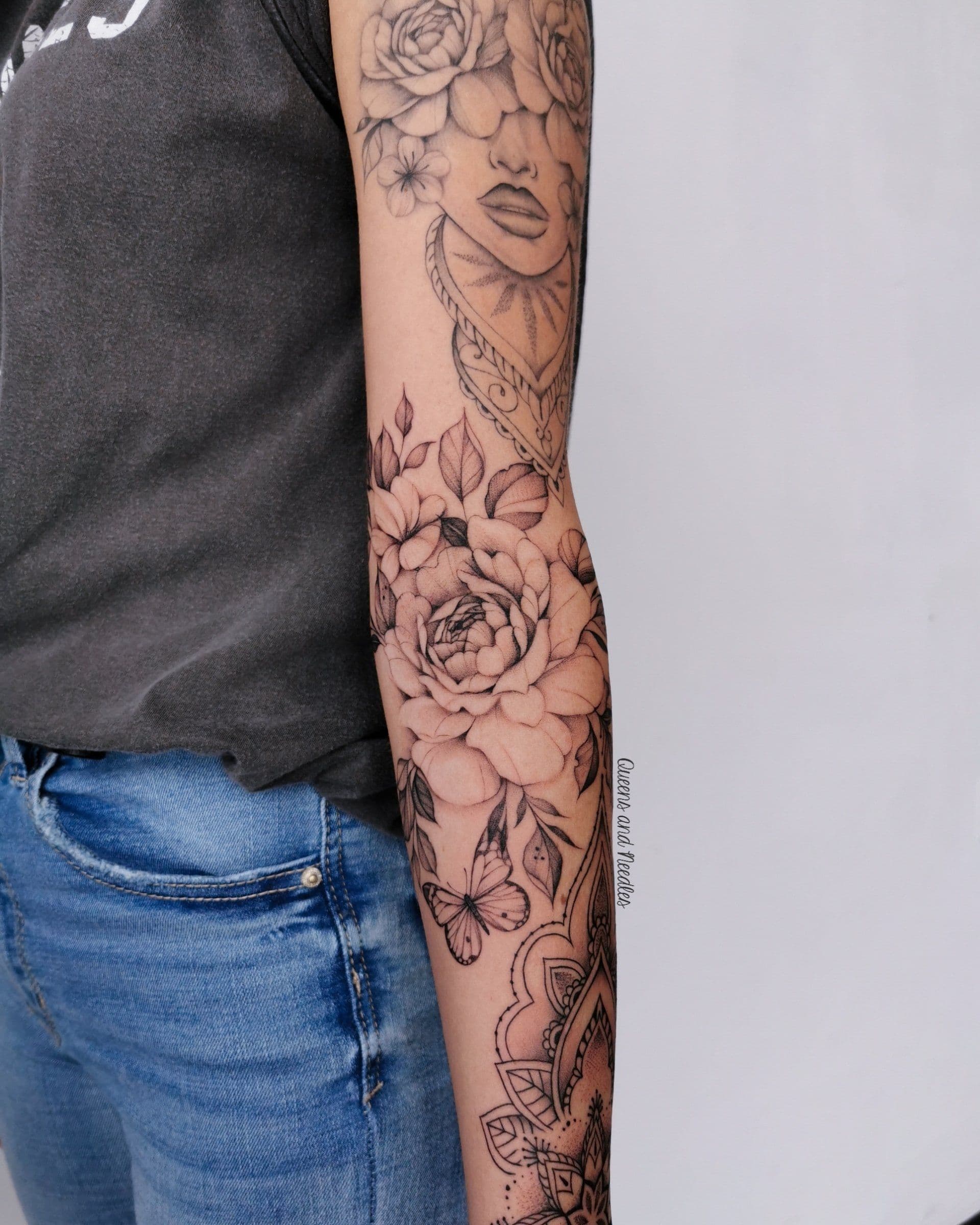 Zwart-wit sleeve met bloemen, vlinder, portret en mandala op arm.
