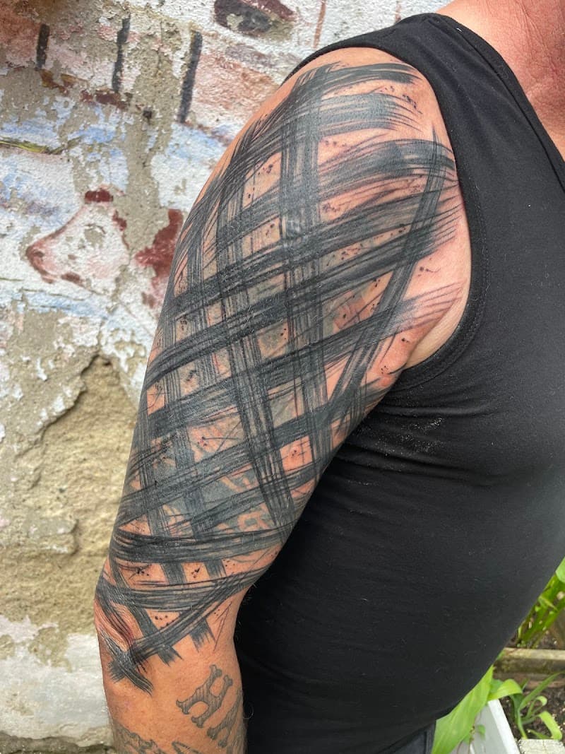 Abstracte zwarte penseelstreken op bovenarm.