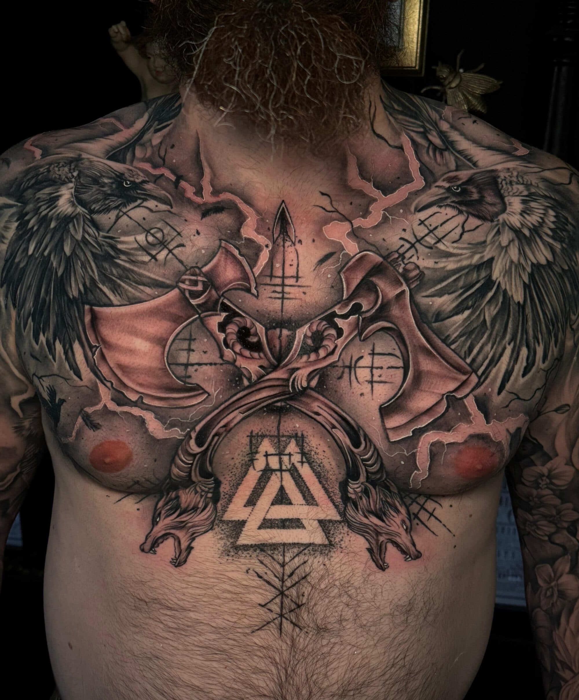 Grote Viking borsttattoo met raven, bijlen, valknut en wolven.
