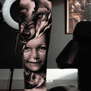 Realistisch portret van kind en wolf op onderbeen.