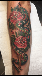 Traditionele slang en rozen tattoo op onderarm.