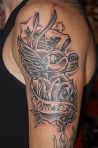 Zwart-wit tattoo van zwaluw, roos en 'MOM DAD' banner op bovenarm.