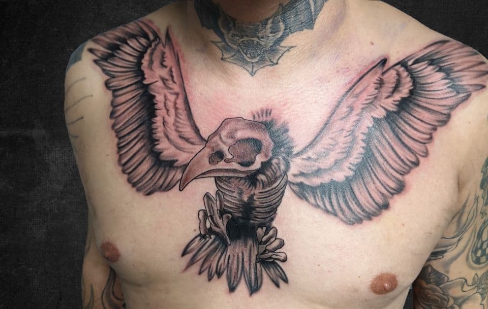 Zwart-witte vogelschedel met vleugels op borst.