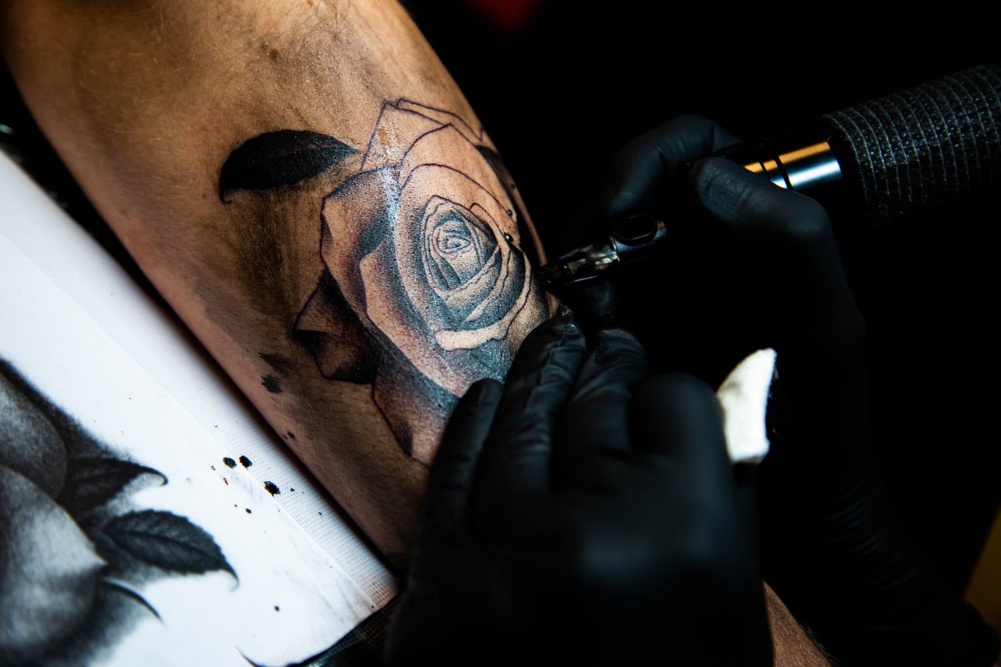 Realistische roos tattoo in wording op bovenarm.