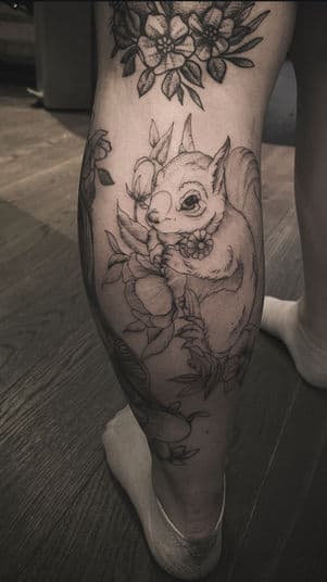 Fineline tattoo van een eekhoorn met bloemen op het onderbeen.