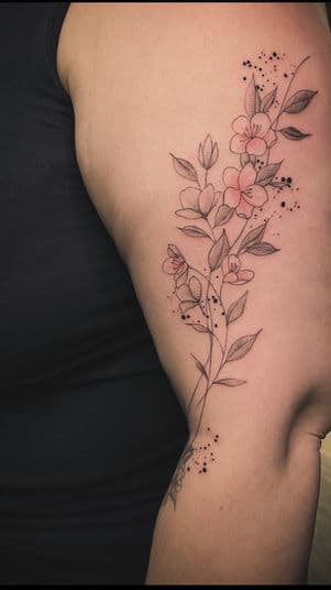 Fineline bloementak met dotwork op bovenarm.