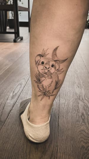 Fineline tattoo van een schattige koala met eucalyptus en een maan op het onderbeen.