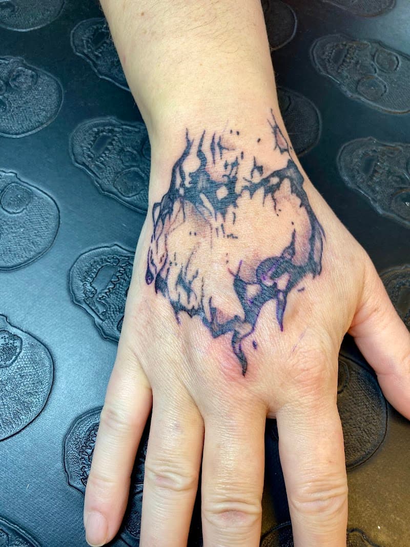 Abstracte, donkere tattoo op de bovenkant van een hand.