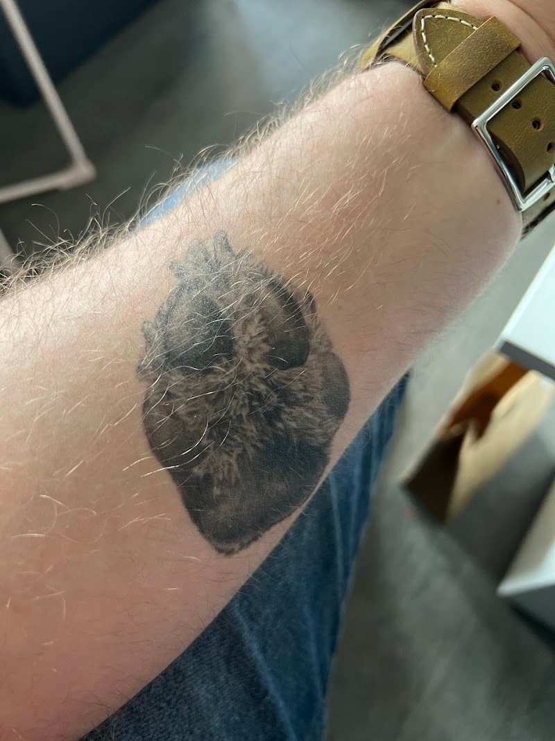 Donkere blackwork tattoo van een anatomisch hart op de onderarm.