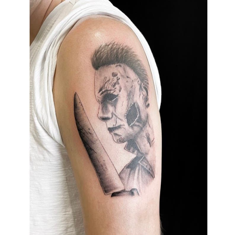 Realistische Michael Myers met mes op bovenarm.