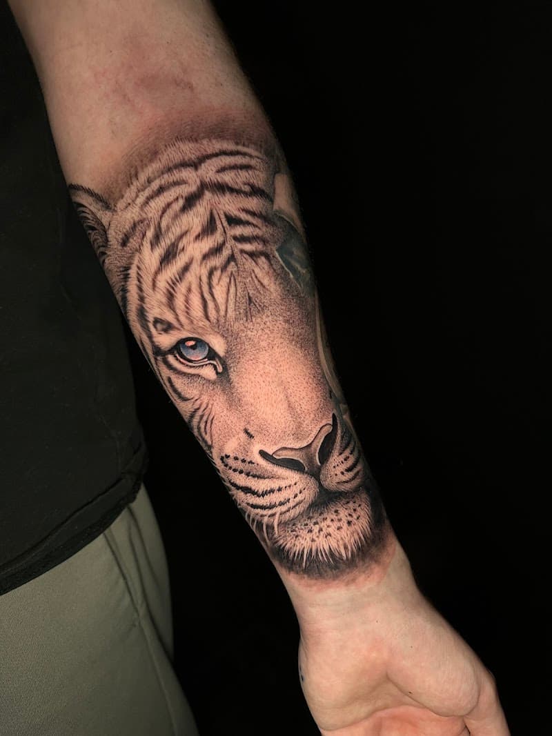 Realistische tijgerkop met blauw oog op onderarm.