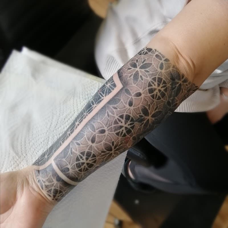 Geometrische dotwork half-sleeve met flower of life patroon en negatieve ruimte.