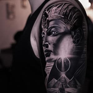 Realistische zwart-wit tattoo van een farao, piramides en een eclips op de bovenarm.