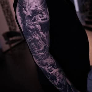 Gedetailleerde zwart-wit tattoo van een engel die een demon verslaat op een arm.