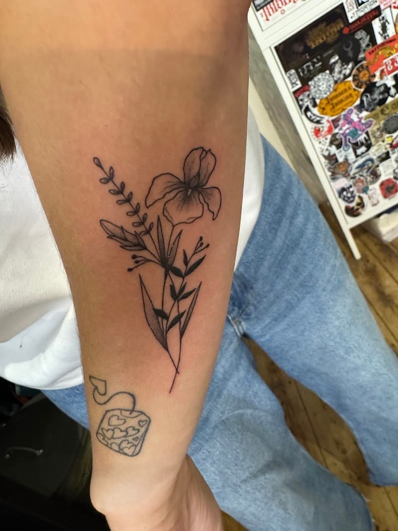 Fineline bloemen en theezakje op onderarm.