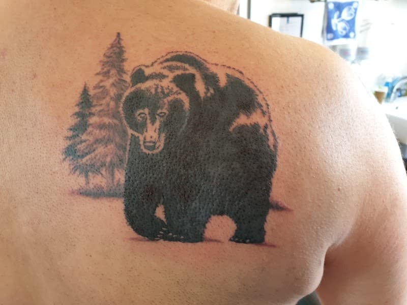 Zwart-witte beer met bomen op schouderblad.