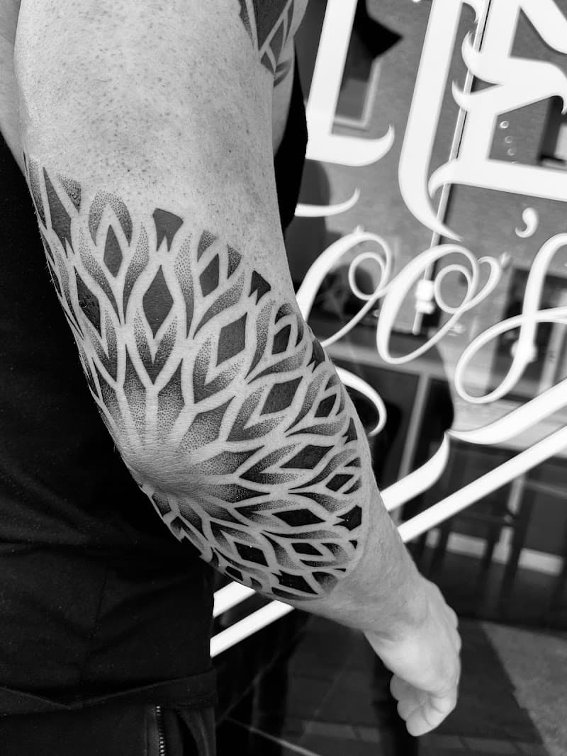 Geometrische dotwork mandala tattoo op de elleboog.
