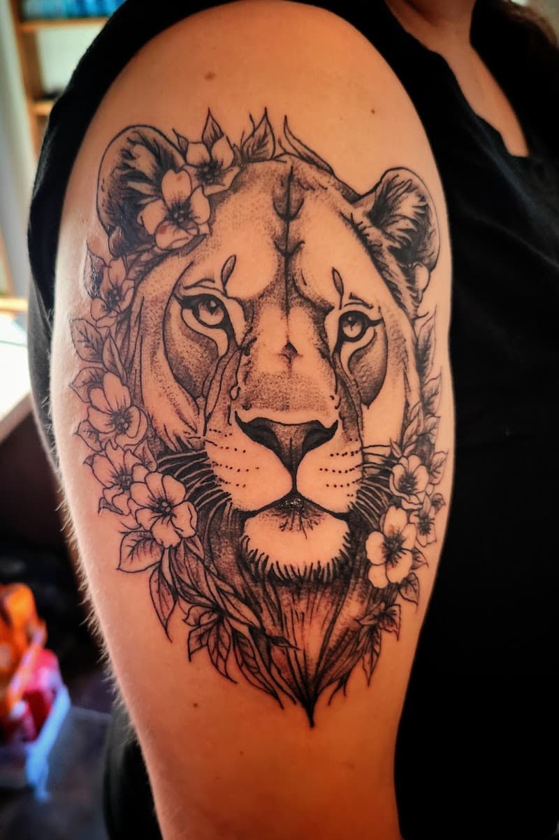 Blackwork leeuwin met bloemen op bovenarm.