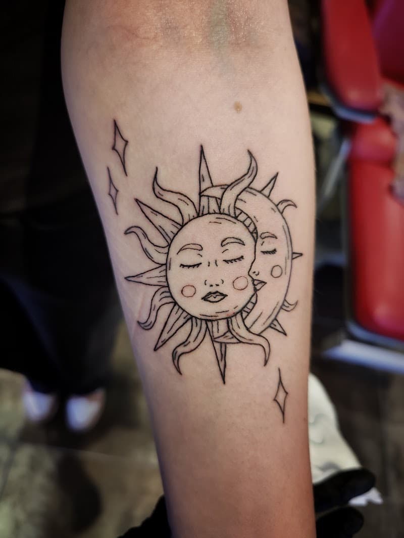 Fineline tattoo van een zon en maan met gezichten en sterren.