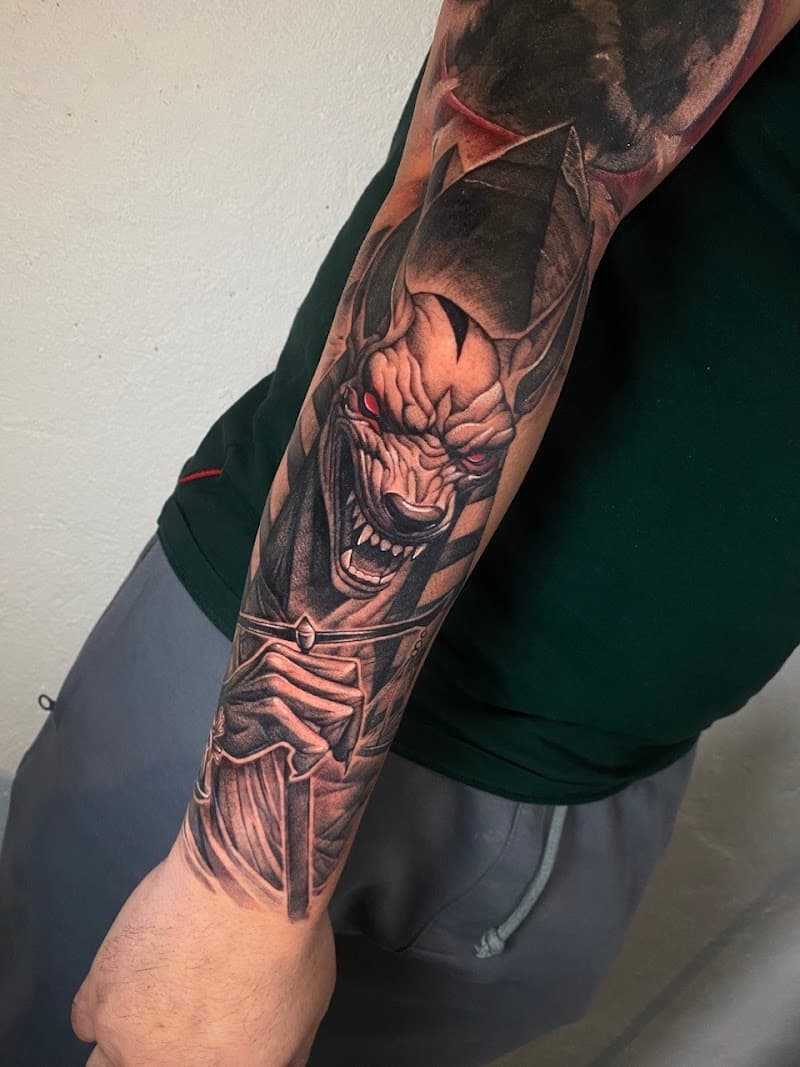 Realistische Anubis tattoo met rode ogen op onderarm.