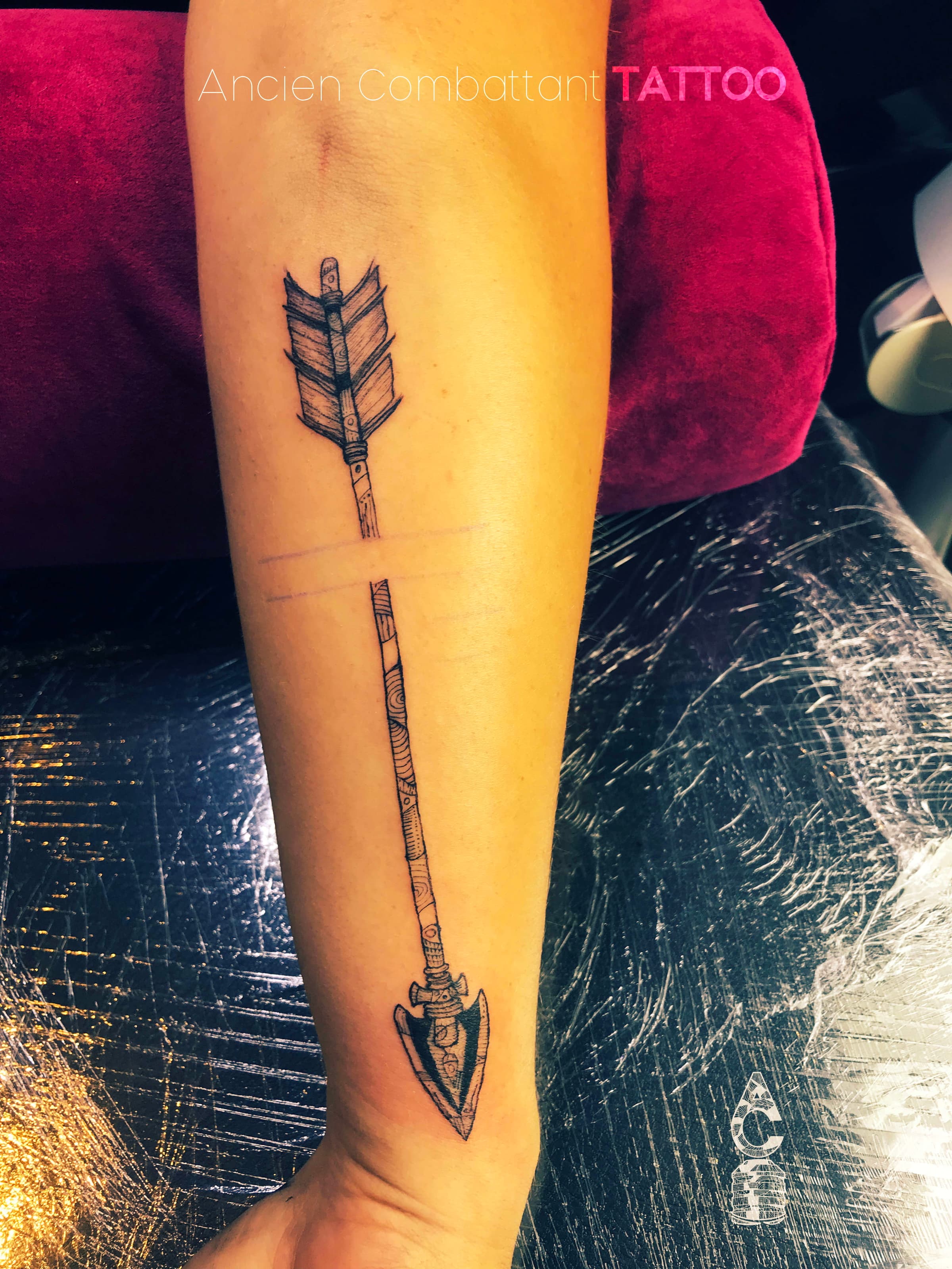 Gedetailleerde blackwork pijl tattoo op de onderarm met patronen.