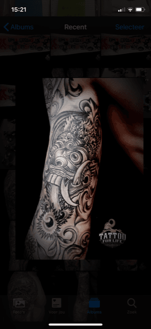 Zwart-wit Balinees Barong masker tattoo op bovenarm.