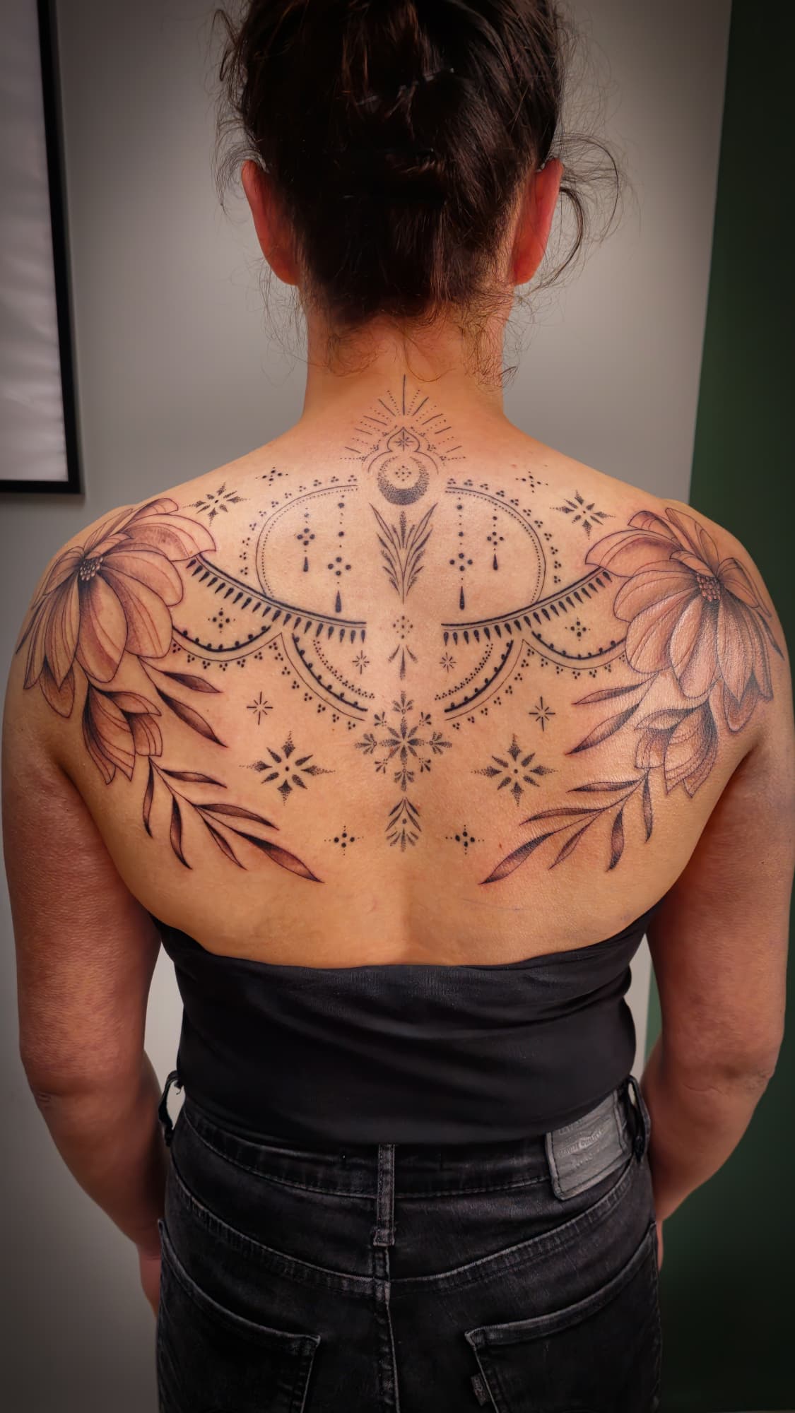Grote rugtattoo met bloemen en geometrische dotwork patronen.