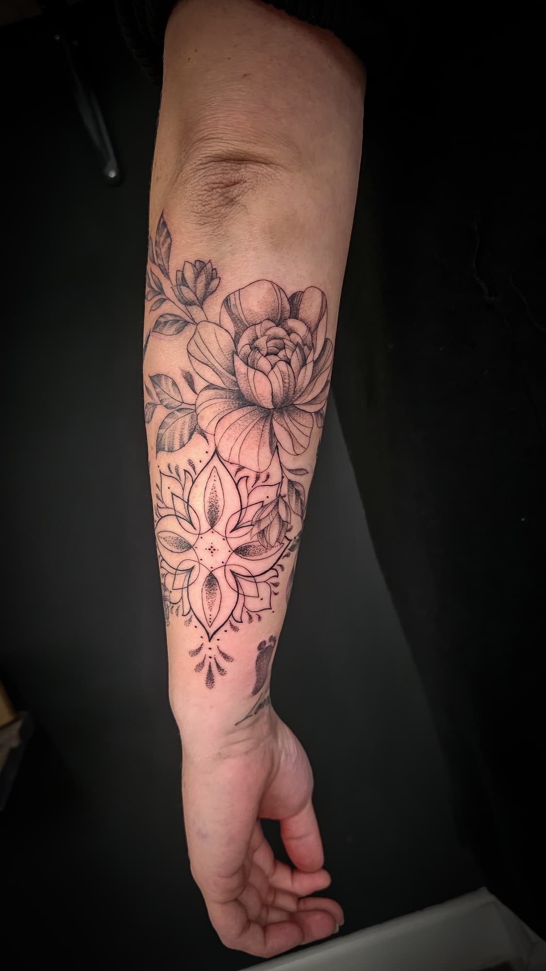 Fineline bloem en mandala op onderarm.