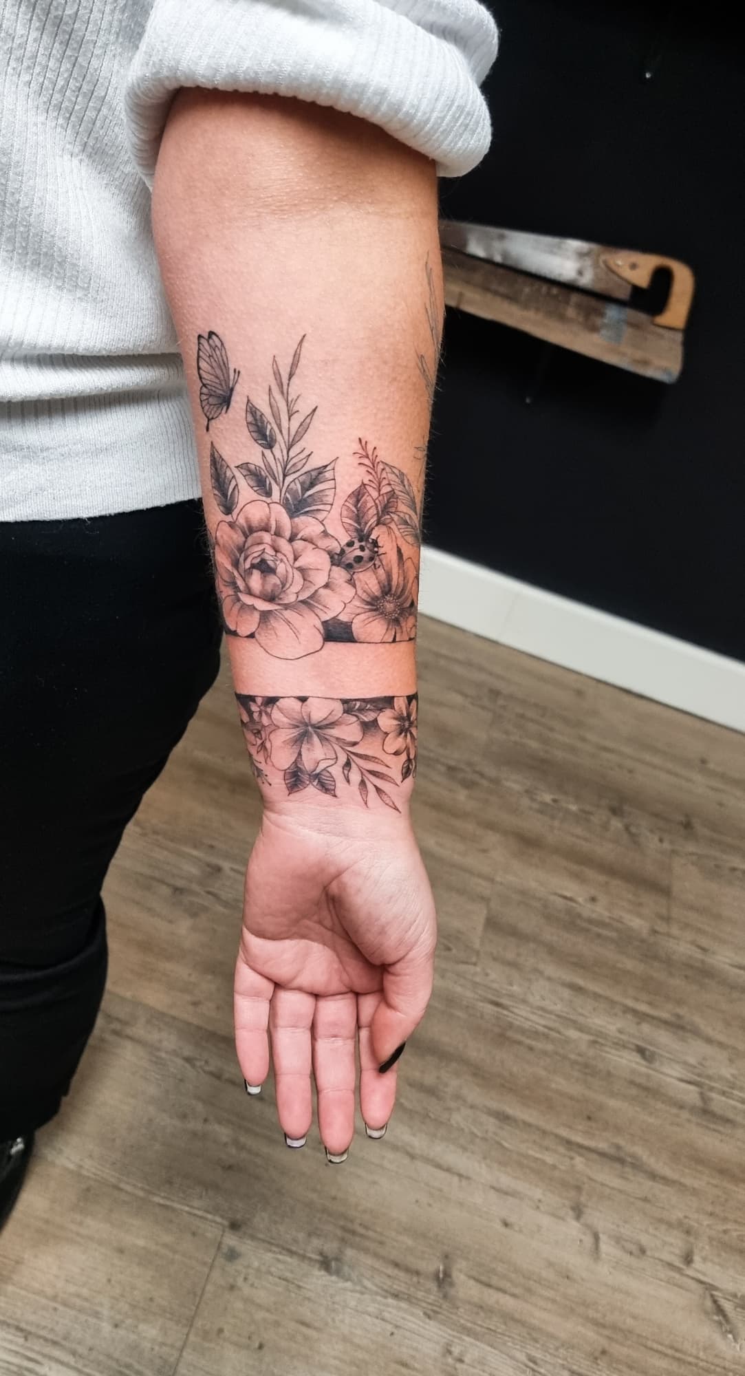 Twee bloemenbanden met vlinder en lieveheersbeestje op onderarm.