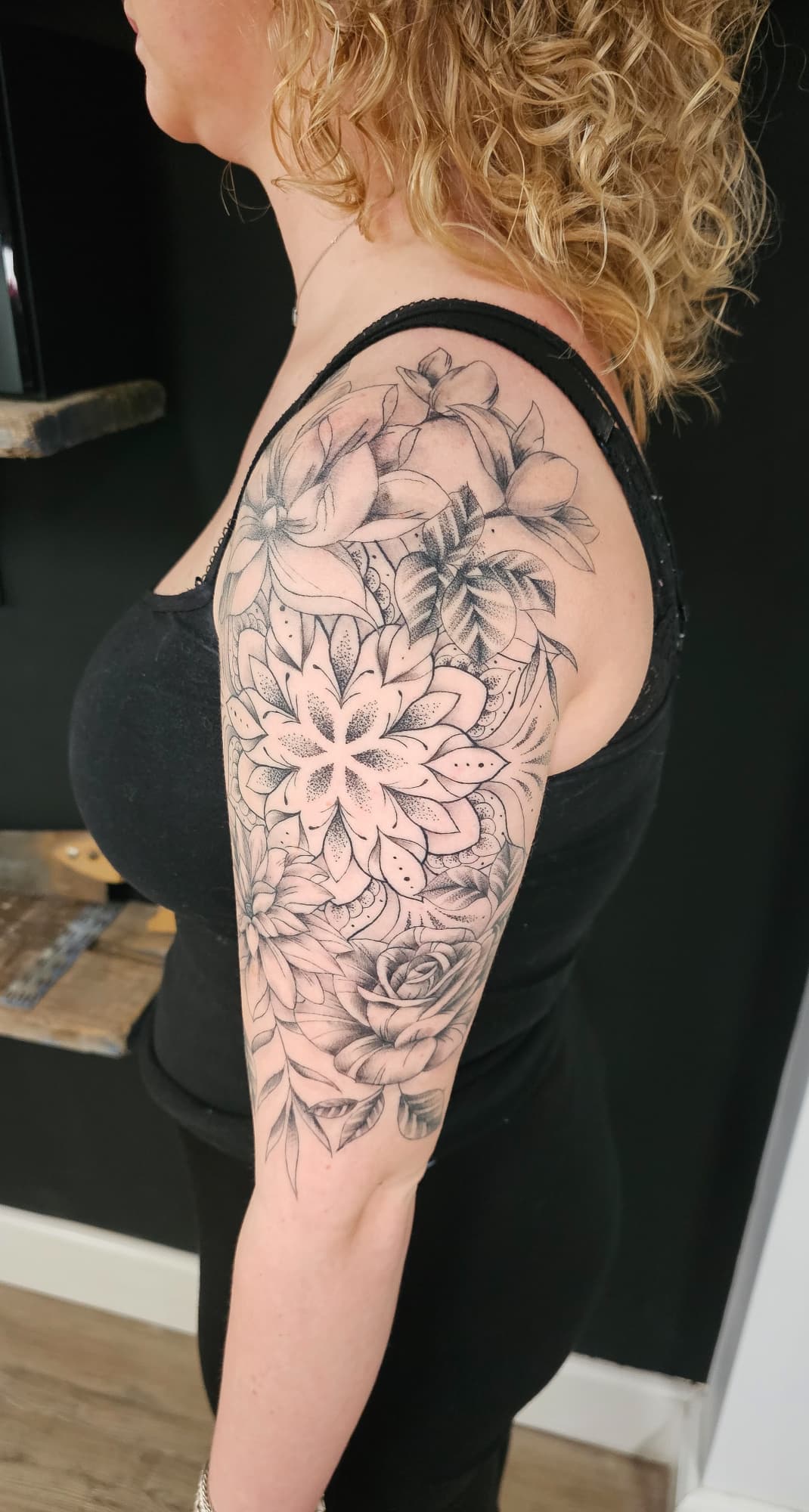 Grote mandala en bloemen half-sleeve tattoo op bovenarm.