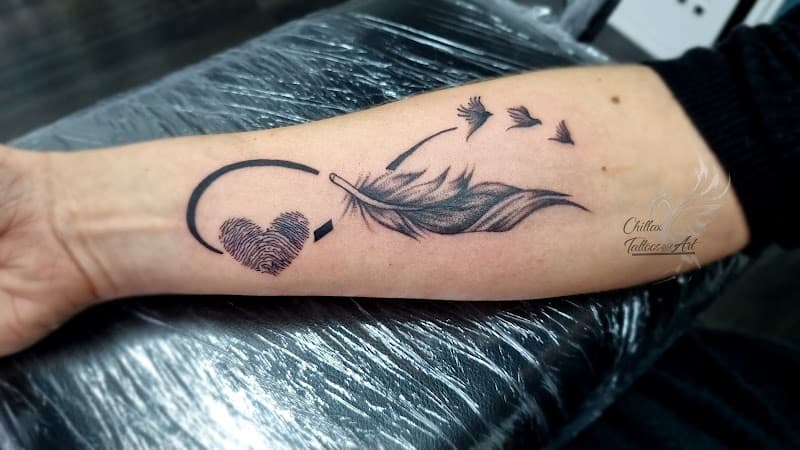 Infinity symbool met veer, vingerafdruk hart en vogels op onderarm.