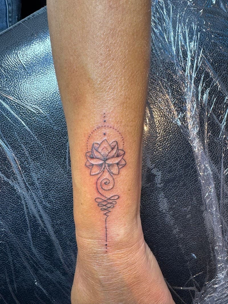 Fineline unalome met lotusbloem op pols.