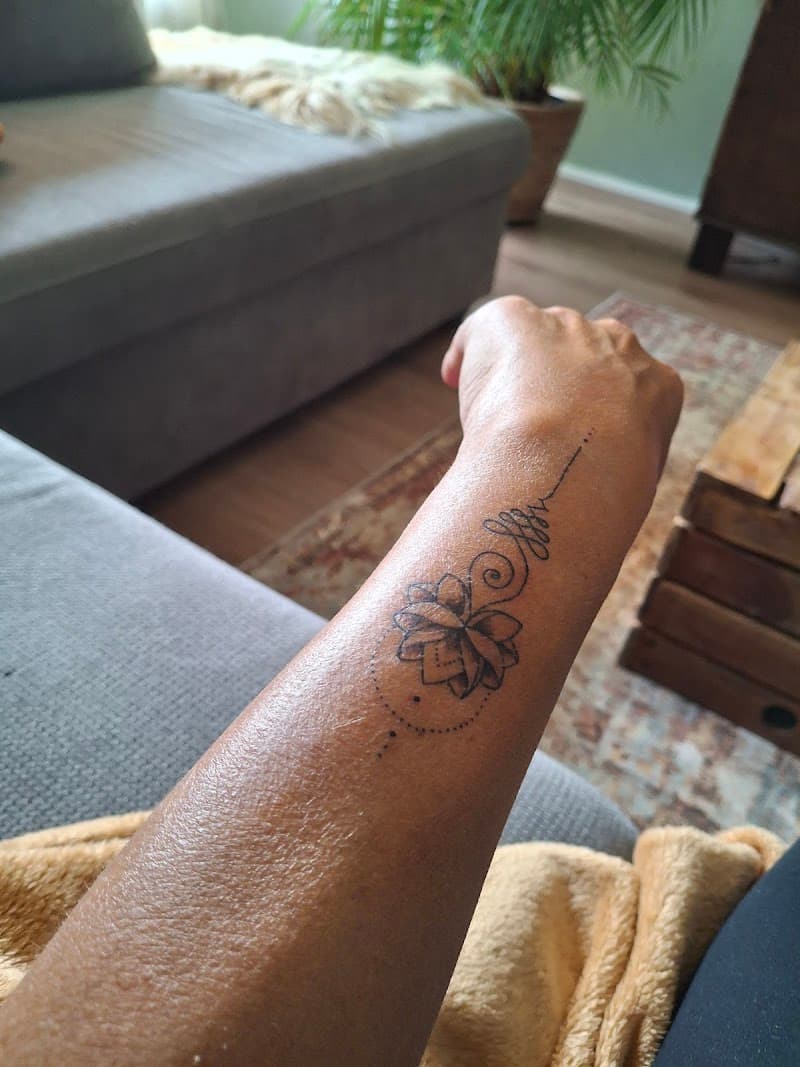 Fineline unalome en lotusbloem tattoo op onderarm.