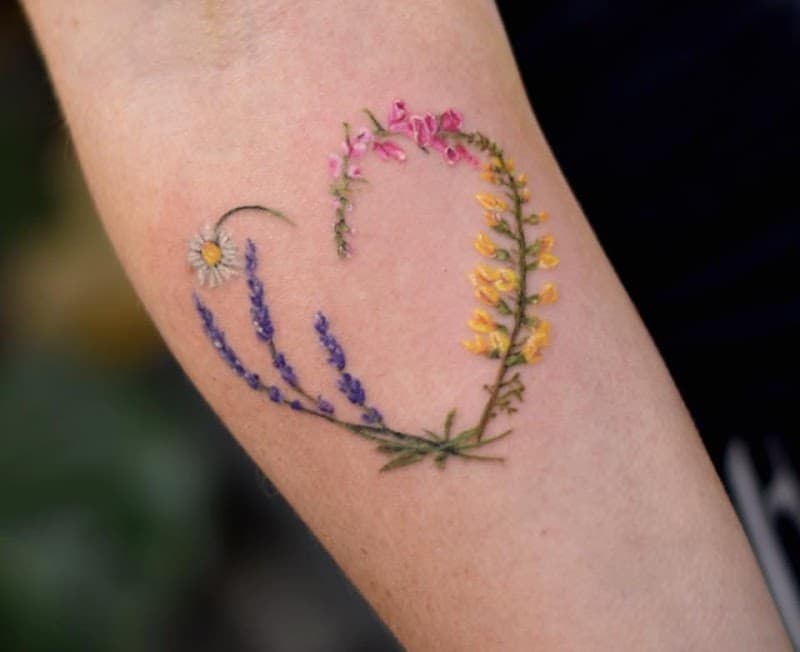 Klein hartje van wilde bloemen (madeliefje, lavendel) op arm.