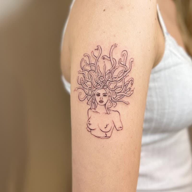 Fineline Medusa buste tattoo op bovenarm.