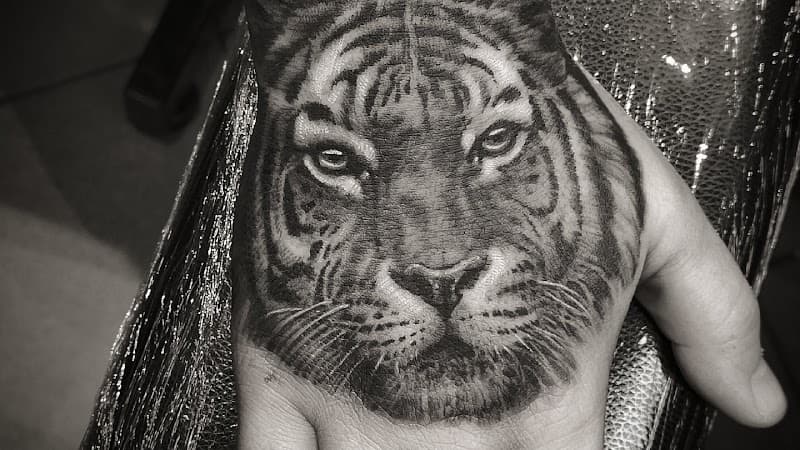 Realistische tijgerkop tattoo op de handpalm.