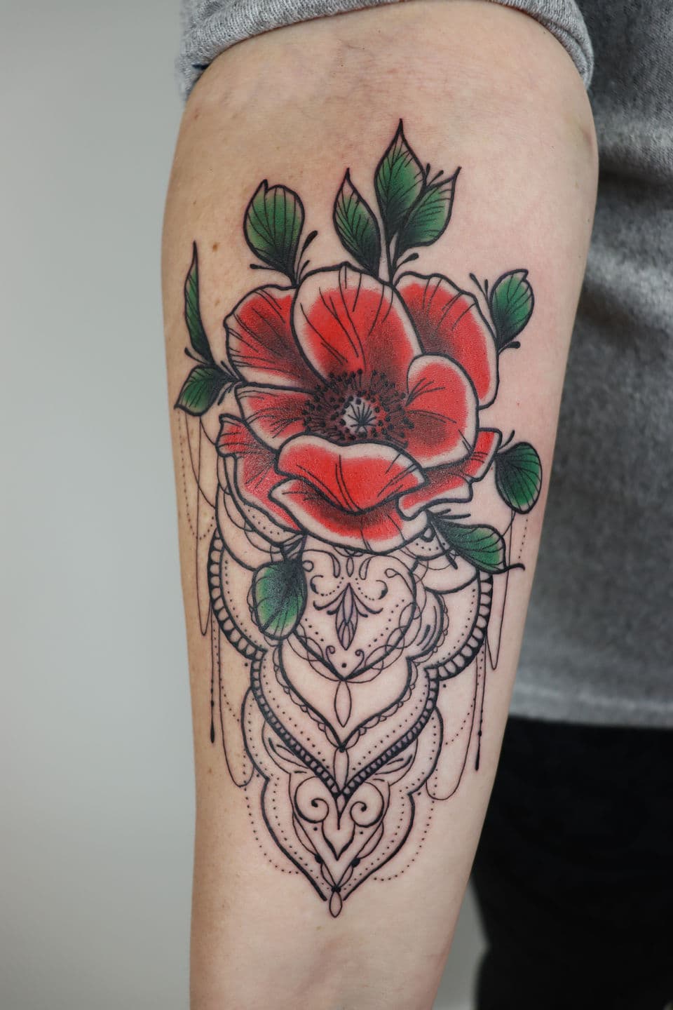 Rode klaproos met sierlijk mandala en kantwerk patroon eronder.