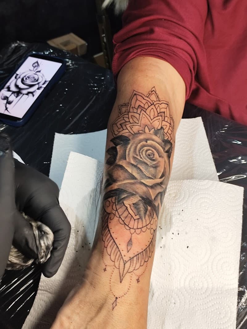 Zwart-wit roos met mandala en ornamenten op onderarm.