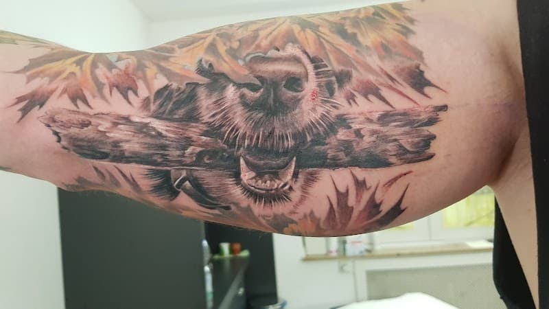 Realistische tattoo van een hondensnuit met een stok, tussen herfstbladeren.