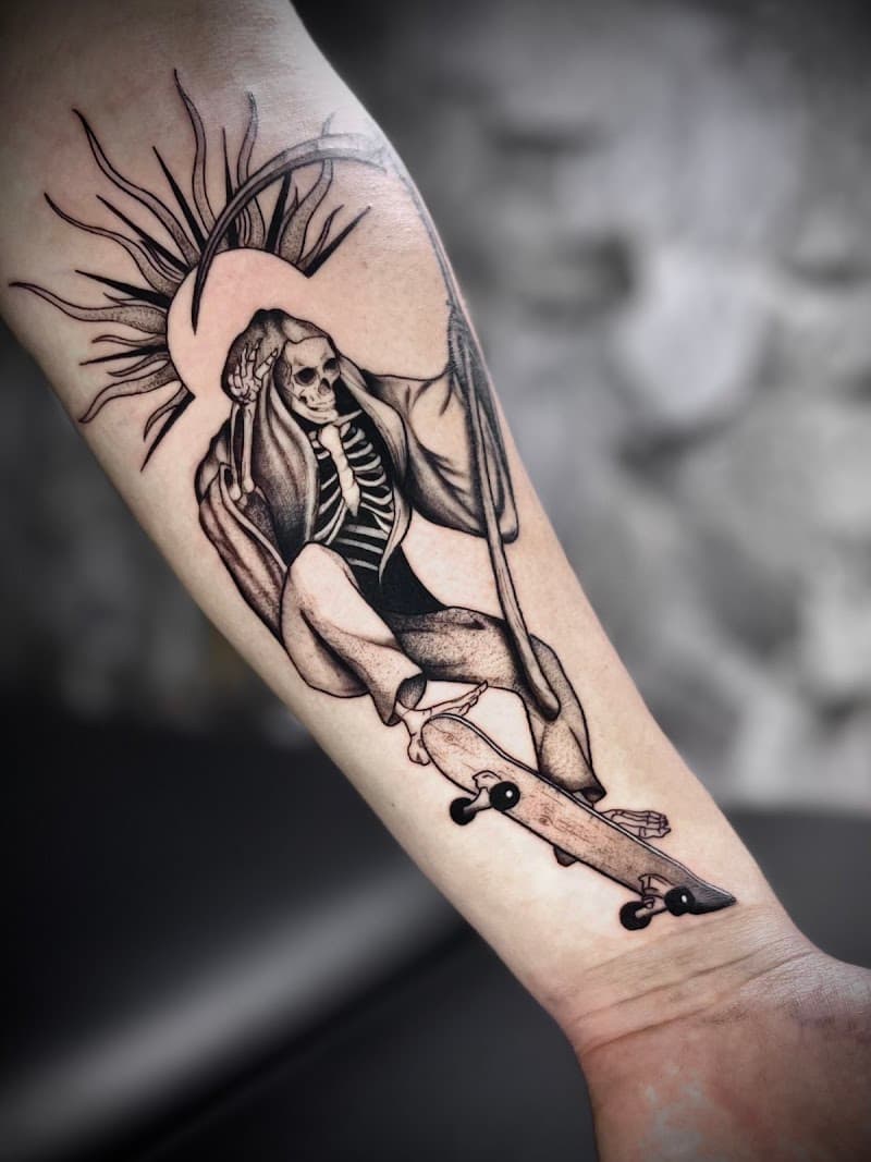 Zwart-wit tattoo van een skatende Magere Hein met zeis en stralenkrans.