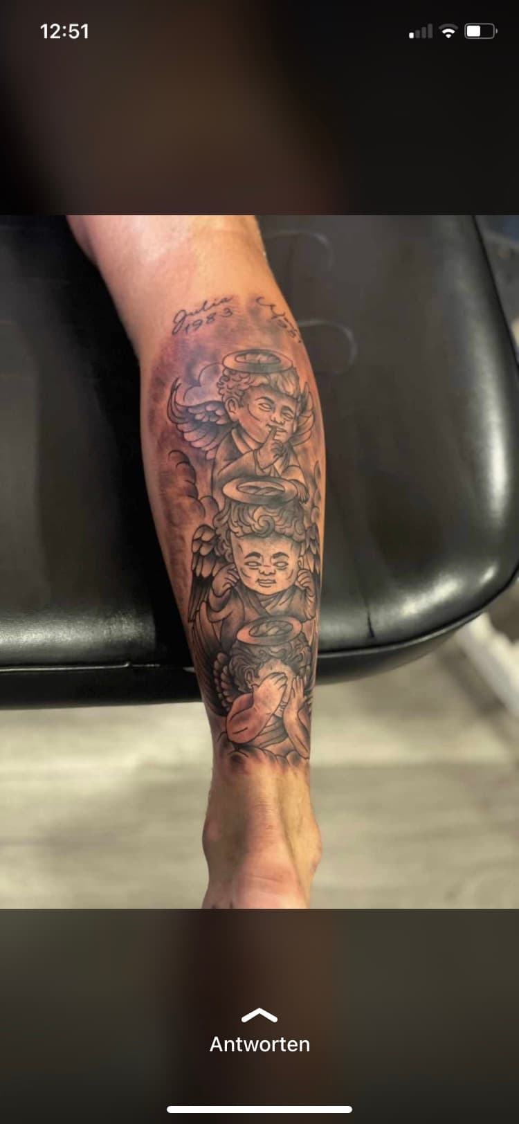 Zwart-grijze tattoo van drie cherubijntjes (horen, zien, zwijgen) op onderbeen.