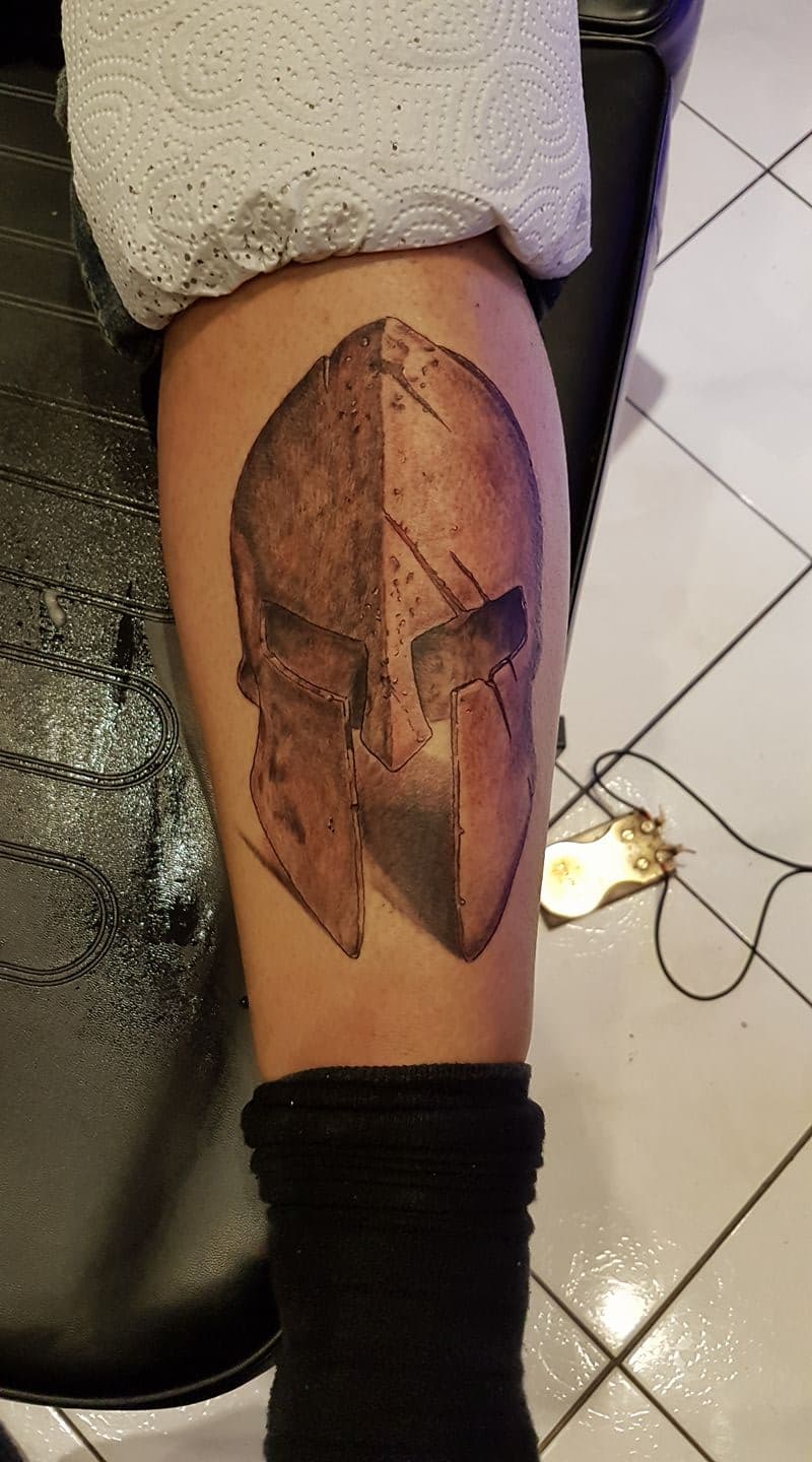 Realistische Spartaanse helm tattoo op onderbeen.