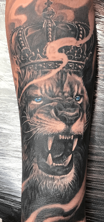 Realistische leeuw met kroon en blauwe ogen op onderarm.