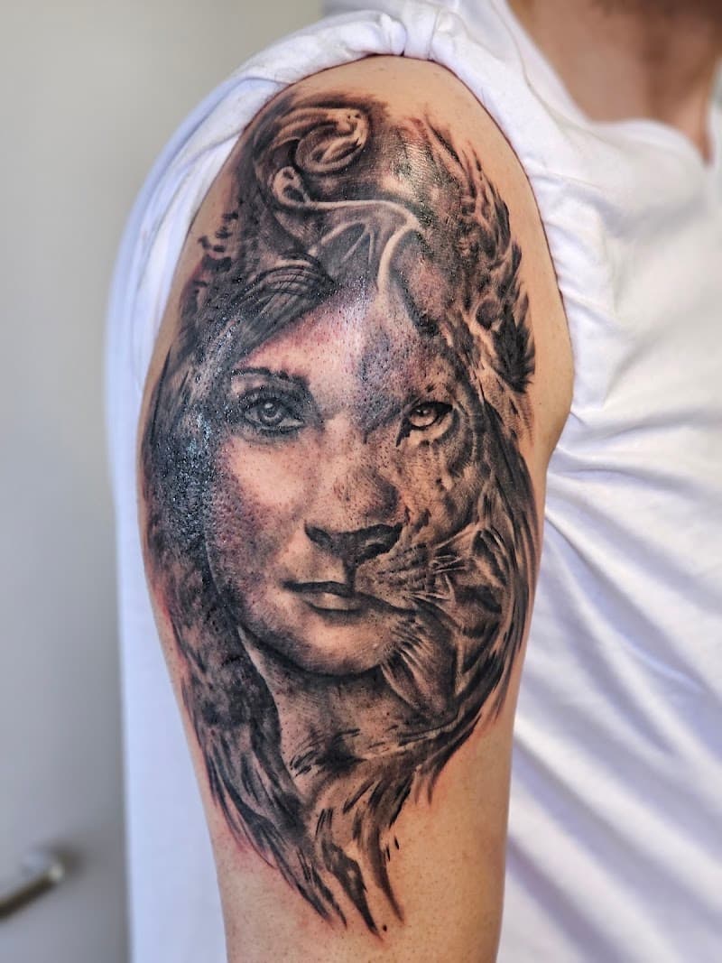 Realistische tattoo van een vrouw en leeuw gezicht die samensmelten op de bovenarm.