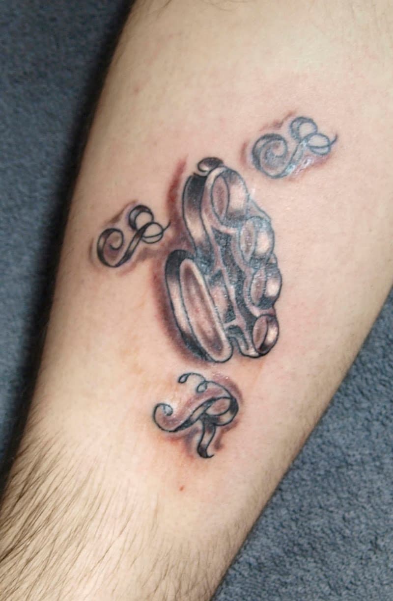 Black and grey boksbeugel tattoo met sierlijke letters op onderbeen.