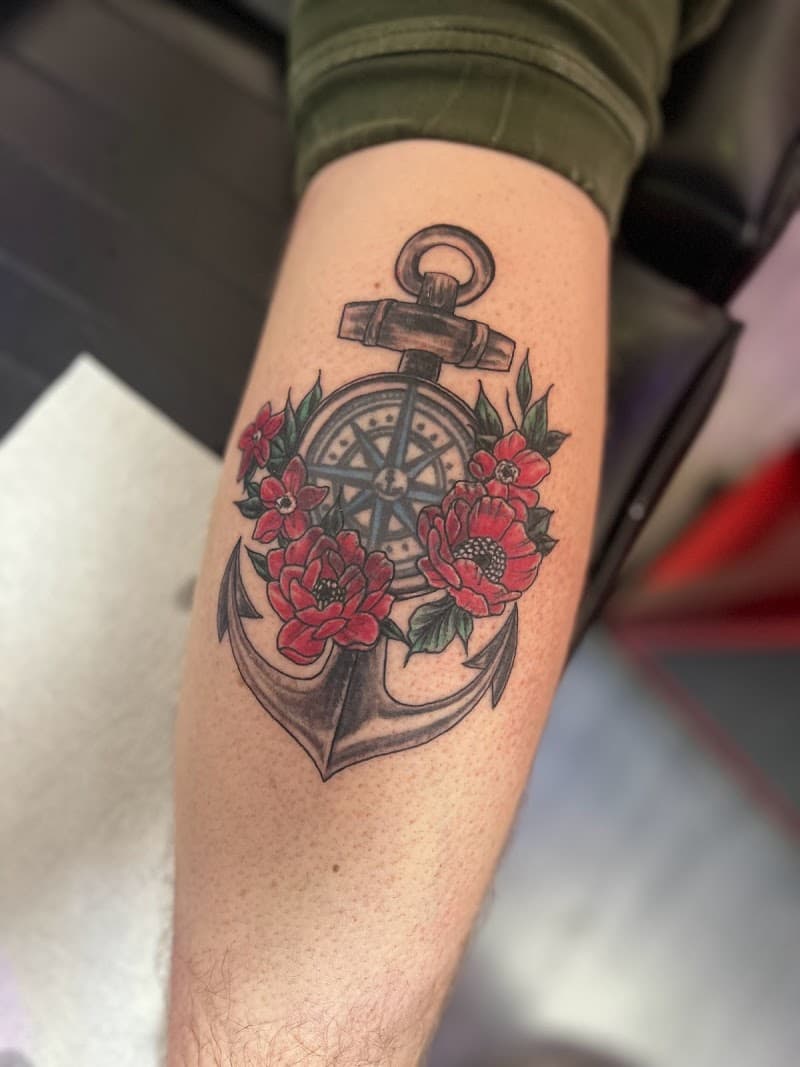 Anker met kompas en rode bloemen op onderbeen.